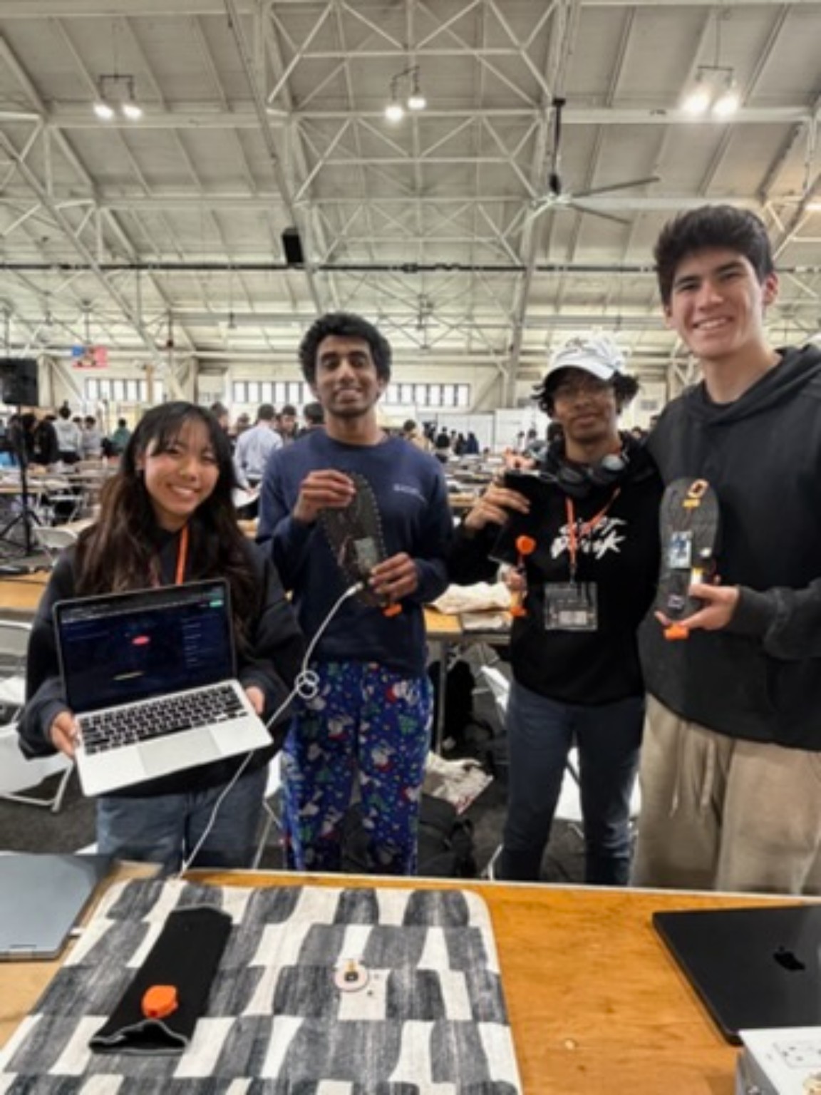 Hudson Etkin, Sherry Li, Rohan Bala, and Apoorva holding the insoles and prototype, with the laptop present.