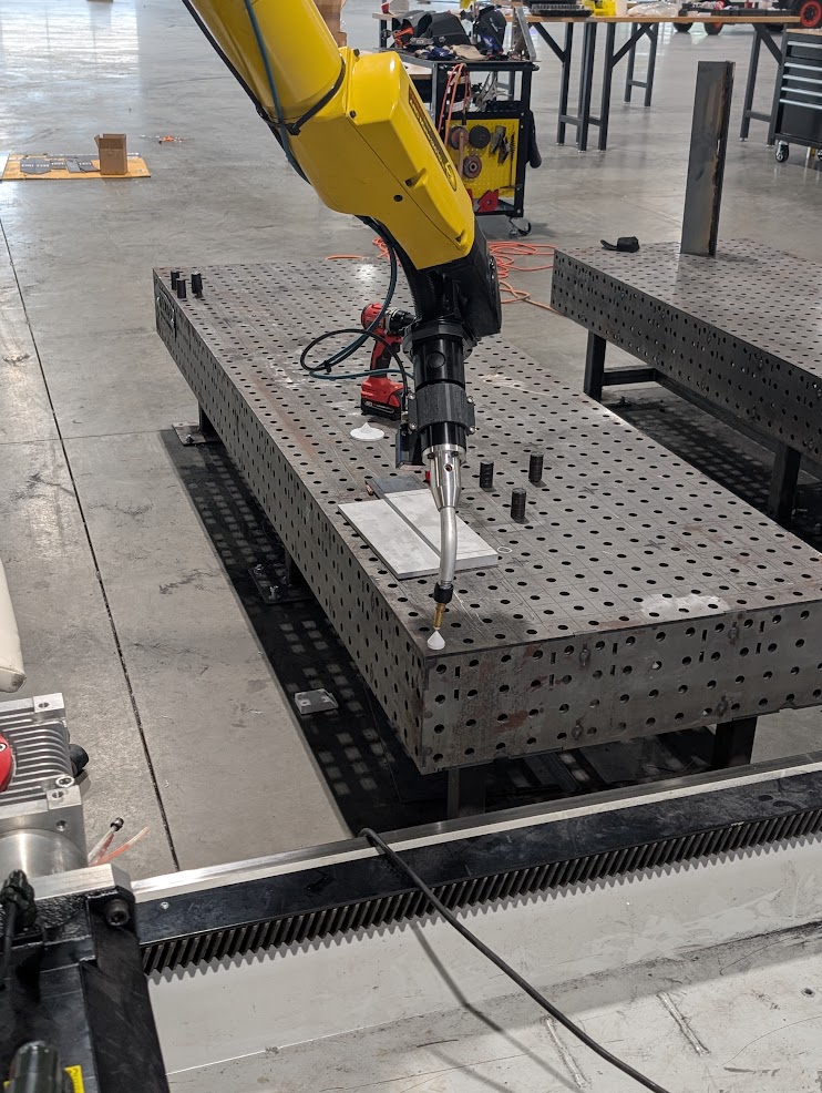 FANUC robot over the perforated fixture table during a calibration setup.